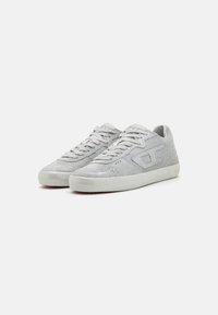 Sneakers grigi in tessuto testurizzato con finitura metallica. Presentano una punta morbida e una suola in gomma. I lacci sono di un grigio chiaro.