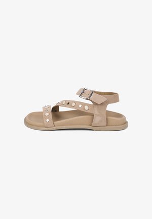 Beige flache Sandale mit Knöchelriemen, silberner Schnalle und dekorativen runden Metallnieten an Wildlederriemen.