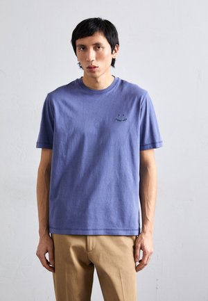 Fioletowa bawełniana koszulka z krótkim rękawem i okrągłym dekoltem, z małym zielonym haftowanym wzorem na piersi, gładka w dotyku.