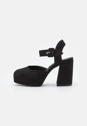 Czarne zamszowe platformy na wysokim obcasie z zaokrąglonym noskiem, szerokim obcasem blokowym i paskiem na kostkę z zapięciem. Gładka struktura na całej powierzchni.