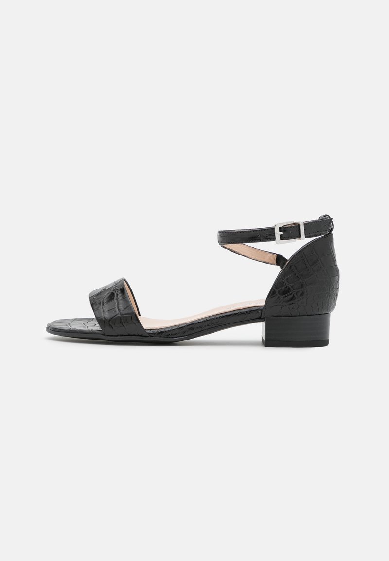Sandal à talon bas noir avec texture crocodile, bout ouvert, sangle à la cheville avec boucle argentée sur fond blanc.