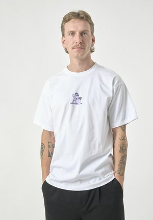 White cotton t-shirt with short sleeves, featuring a cartoon design on the chest in purple and green. Relaxed fit, minimalistic style.