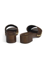 Braune Holzplattform-Sandalen mit geschwungenen Riemen und goldenen Nieten entlang des äußeren Randes. Flache Fußbett und dicker Absatz mit strukturierter Oberfläche.