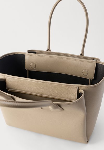 Μπεζ δερμάτινη τσάντα ώμου με μακριά χερούλια, διαθέτει ανοιχτό κύριο διαμέρισμα και εσωτερική τσέπη με φερμουάρ.