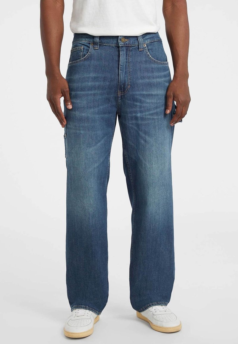 Lichtblauwe denim jeans met een recht model, vijf zakken en een subtiele vervaging. Gepaard met witte sportschoenen.