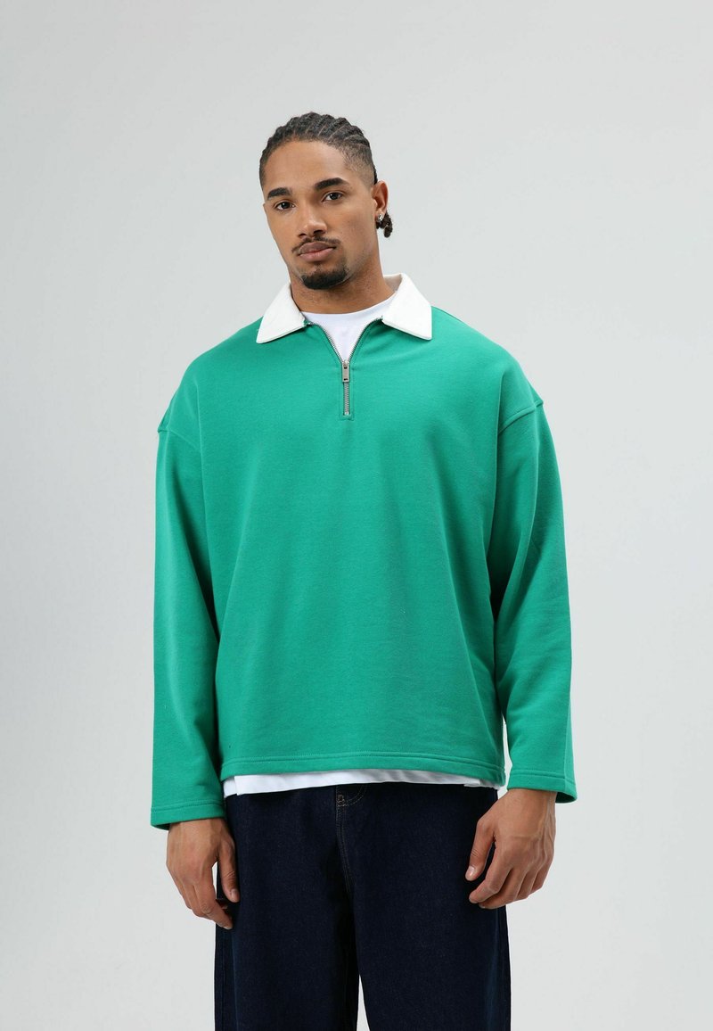 Groene trui met een witte kraag en ritssluiting, met een ontspannen pasvorm en lange mouwen, gemaakt van zachte, gestructureerde stof.