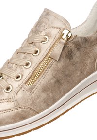 Beige suède sneaker met gouden ritssluiting en oogjes, beige veters en een witte rubberen zool met bruine profielzool.