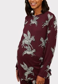Maternity top in burgundy with long sleeves and flying zebra print in black and white. Soft material with slight drape and subtle side slits.
