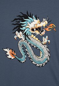 Blauwe T-shirt met een afbeelding van een woeste draak met witte schubben, een zwarte manen en oranje accenten, prachtig gedetailleerd.