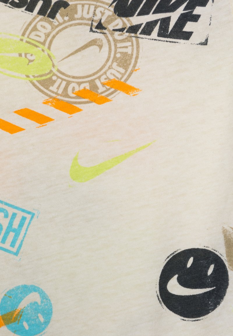 Biała tkanina z różnymi graficznymi nadrukami w kolorach czarnym, pomarańczowym, niebieskim i zielonym. Zawiera logo Nike oraz wesołe tekstowe wzory.