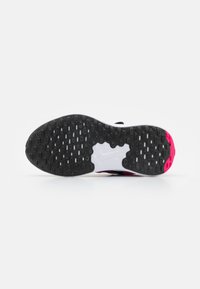 Schwarze und weiße Sportschuhsohle mit einem strukturierten Grip-Muster, das pinke Akzente und ein weißes Markenlogo aufweist.
