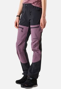 Sort og lilla udendørsbukser med lynlåslommer, forstærkede knæ og justerbare manchetter, lavet af slidstærkt, vandafvisende stof.