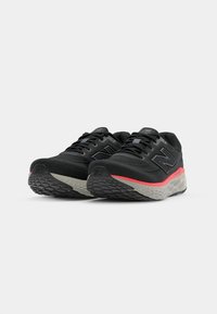 Schwarze Sportschuhe mit Mesh-Obermaterial, grauen Akzenten, gepolstertem Zwischensohlenbereich mit roten Details und strukturierter Gummi-Außensohle.