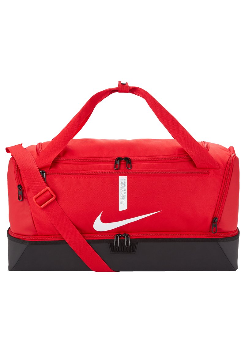 Sac de sport rouge avec base noire, deux zips sur le dessus, un zip à l'avant, sangle d'épaule réglable et logo blanc sur le côté.