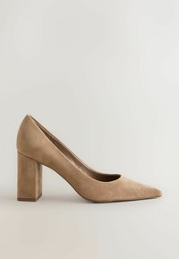 Escarpin beige en daim pour femme avec bout pointu et talon bloc moyen et épais sur un fond clair uni.