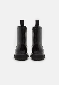 Botas de tobillo de cuero negro con superficie lisa, cierre lateral con cremallera y suelas de goma texturizada. Incluye asas para facilitar su puesta.