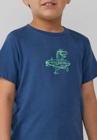 Marineblauw T-shirt van zachte stof met een groene grafische afbeelding van een dinosaurus die surft op een golf, met korte mouwen en een ronde hals.