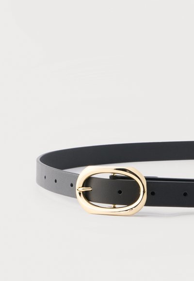 Čierny kožený opasok s viacerými dierkami a lesklou zlatou oválnou prackou na jednoduchom bielom pozadí.