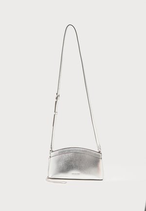 Srebrna metaliczna torebka na ramię z regulowanym paskiem i subtelnym logo z przodu na jednolitym jasnym tle.