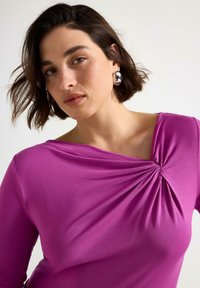 Fuschiafärgad blus med båtringning, vriden detalj vid axeln och långa ärmar, tillverkad av ett mjukt, stretchigt tyg.