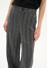 Gestreifte graue Hosen aus leichtem Stoff, mit hohem Bund, vorderem Knopfverschluss und lässiger Passform. Vertikale Streifen sorgen für Textur.