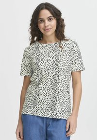 T-shirt a maniche corte color crema con motivo leopardato nero, dotato di scollo rotondo e vestibilità comoda. Tessuto morbido e traspirante.