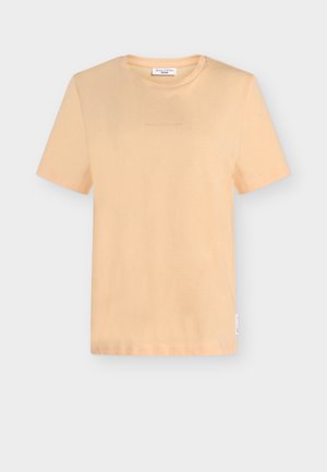 Majica kratkih rokavov barve breskve. Iz mehke tkanine z okroglim izrezom. Nežen logotip natisnjen na prsnem delu. Ravna spodnja roba in sproščen kroj.