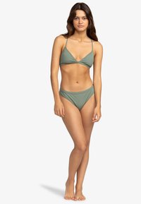 Olivgrön bikini med trekantstopp och justerbara band, kombinerad med lågt skuren trosor, tillverkad av mjukt, stretchigt tyg.