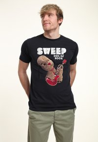 Schwarzes T-Shirt mit einem Grafikdesign eines Plüschhundes, der eine rote E-Gitarre hält, mit dem Text „SWEEP DOG OF ROCK“ in fetter weißer Schrift.
