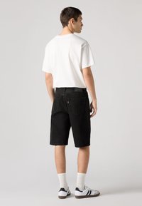 Črni denim kratke hlače z udobnim krojem, kombinirane z belo bombažno majico. Imajo dva zadnja žepa in črne šive.