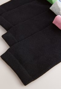 Chaussettes noires avec bords côtelés, présentées pliées. Dessus de chaussettes supplémentaires en couleurs pastel : vert, bleu, rose et gris.