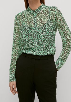 Blusa verde trasparente con un sottile motivo astratto in diverse sfumature. Presenta un colletto alto e una chiusura con bottoni davanti.