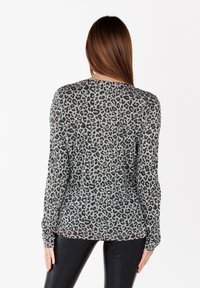 Leopard print long-sleeve top in grey with black patterns. Features a relaxed fit and ribbed cuffs with slight pink accents. Soft fabric.