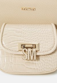 Sac à main beige en relief crocodile avec une texture lisse, doté d'un fermoir en métal doré affichant "SM" et d'un logo subtil embossé au-dessus.