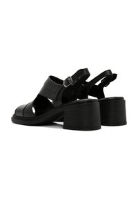 Zwarte leren sandalen met een ronde neus, open zijkanten en een verstelbare enkelband. Voorzien van een tekstuurblokhak en een gestikt zool.
