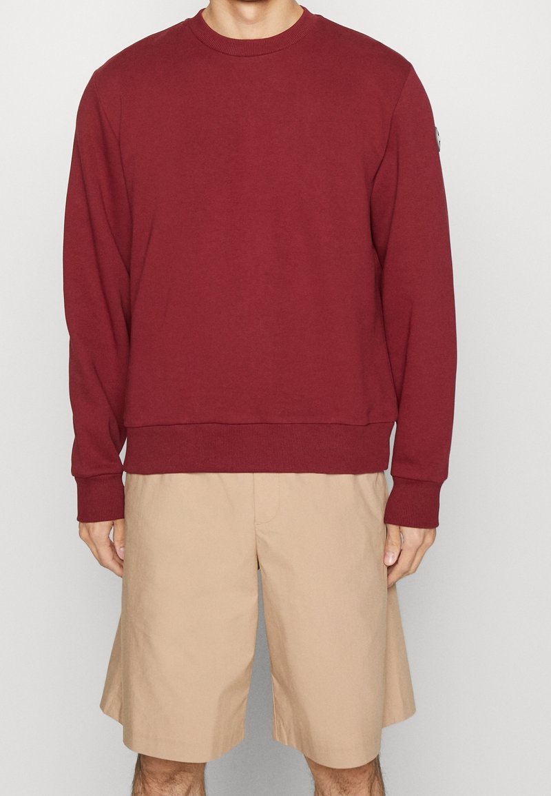 Felpa bordeaux con maniche lunghe, collo e polsini a costine, abbinata a pantaloni corti beige. Tessuto morbido con una vestibilità comoda.