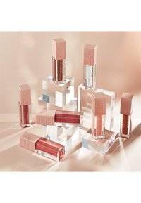 Lifter Gloss lip glosses in clear and various shades are displayed in transparent geometric blocks; features pink square caps with embossed text.