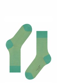 Grüne Socken mit gerippter Textur, ausgestattet mit einem einfarbigen, dunkleren grünen Bündchen und Zehen. Hergestellt aus weichem Material, das ein nahtloses Design zeigt.