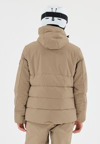 Beige Steppjacke mit Kapuze, die ein gestepptes Design und eine lockere Passform aufweist. Die Rückansicht zeigt die glatte Textur und verstellbare Elemente.