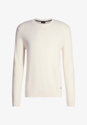 Cremefarbener Pullover mit Rundhalsausschnitt und langen Ärmeln, dezent strukturiertes Muster und kleines Metallschild mit Markenlogo nahe dem Saum.