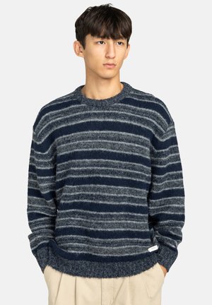 Marineblauwe en grijze gestreepte gebreide trui met een ronde hals en een geribbelde zoom. Heeft een zachte textuur en een losse pasvorm.