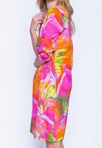 Colorful blomsterkjole med livlige mønstre i pink, orange og grøn. Lavet af letvægtsstof, har den en afslappet pasform og trekvartlange ærmer.