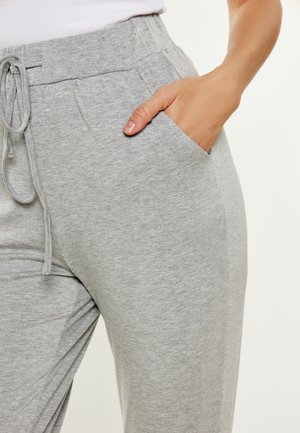 Pantaloni sportivi grigi chiari realizzati in tessuto morbido, con vita elastica e cordino, e tasche laterali. Texture liscia e vestibilità comoda.