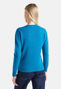 Světlý modrý svetr vyrobený z měkkého materiálu, s žebrovaným lemem a manžetami, klasickým kulatým výstřihem a dlouhými rukávy.