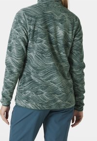Fleece pullover in het groen met golfpatroon, hoge kraag, lange mouwen en een textuurafwerking, gecombineerd met blauwe broek.