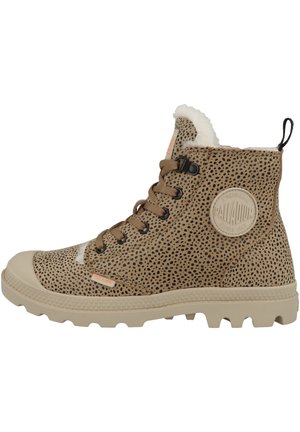 Bottine en toile marron avec des éclaboussures noires, col en fausse fourrure blanche, semelle en caoutchouc beige et patch logo rond sur le côté extérieur.