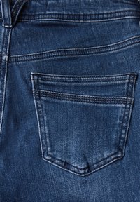 Jean en denim bleu foncé avec une poche arrière. Présente des coutures visibles et une texture légèrement décolorée. La poche a une forme rectangulaire.