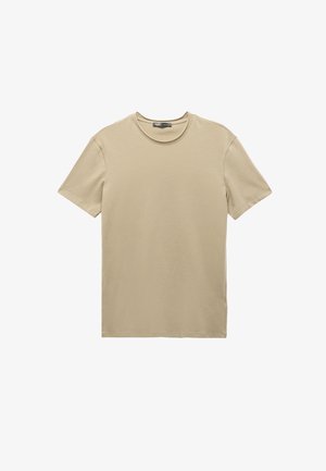 Camiseta de manga corta color beige hecha de algodón suave, con un cuello redondo clásico y un diseño de corte recto sin patrones visibles.