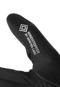 Guanto nero con marchio Windstopper di Gore-Tex Labs. Caratterizzato da un tessuto liscio e strutturato e una vestibilità avvolgente. Cuciture rinforzate lungo i bordi.