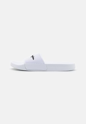 Sandalia deslizante blanca con una correa texturizada, suela plana y un acento de logo negro en la correa. Fabricada con material ligero y duradero.